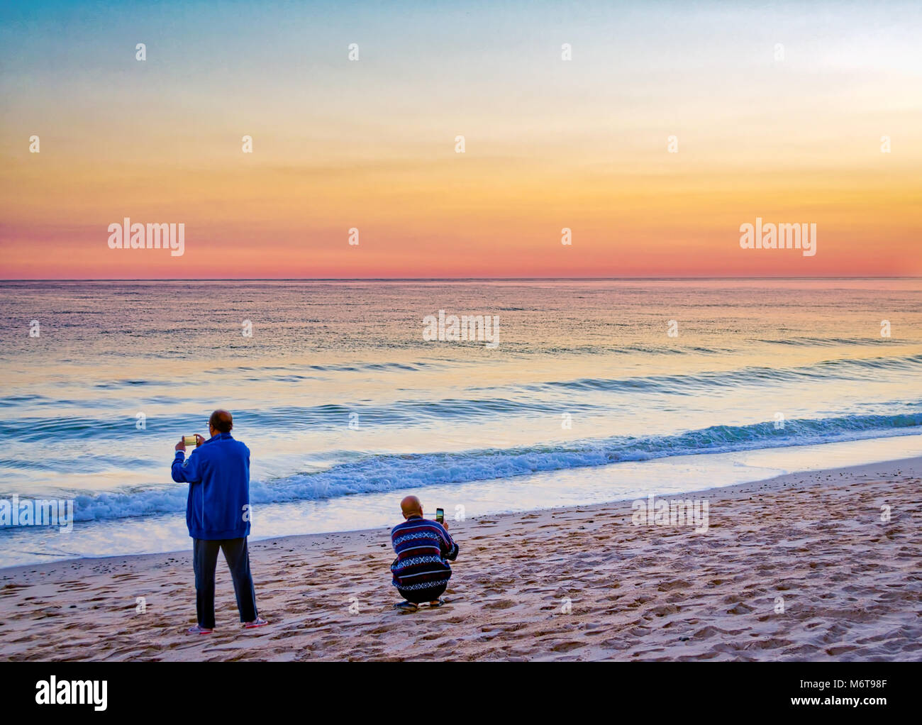 Zurück Blick auf zwei Menschen schießen die majestätische Himmel am Strand Stockfoto