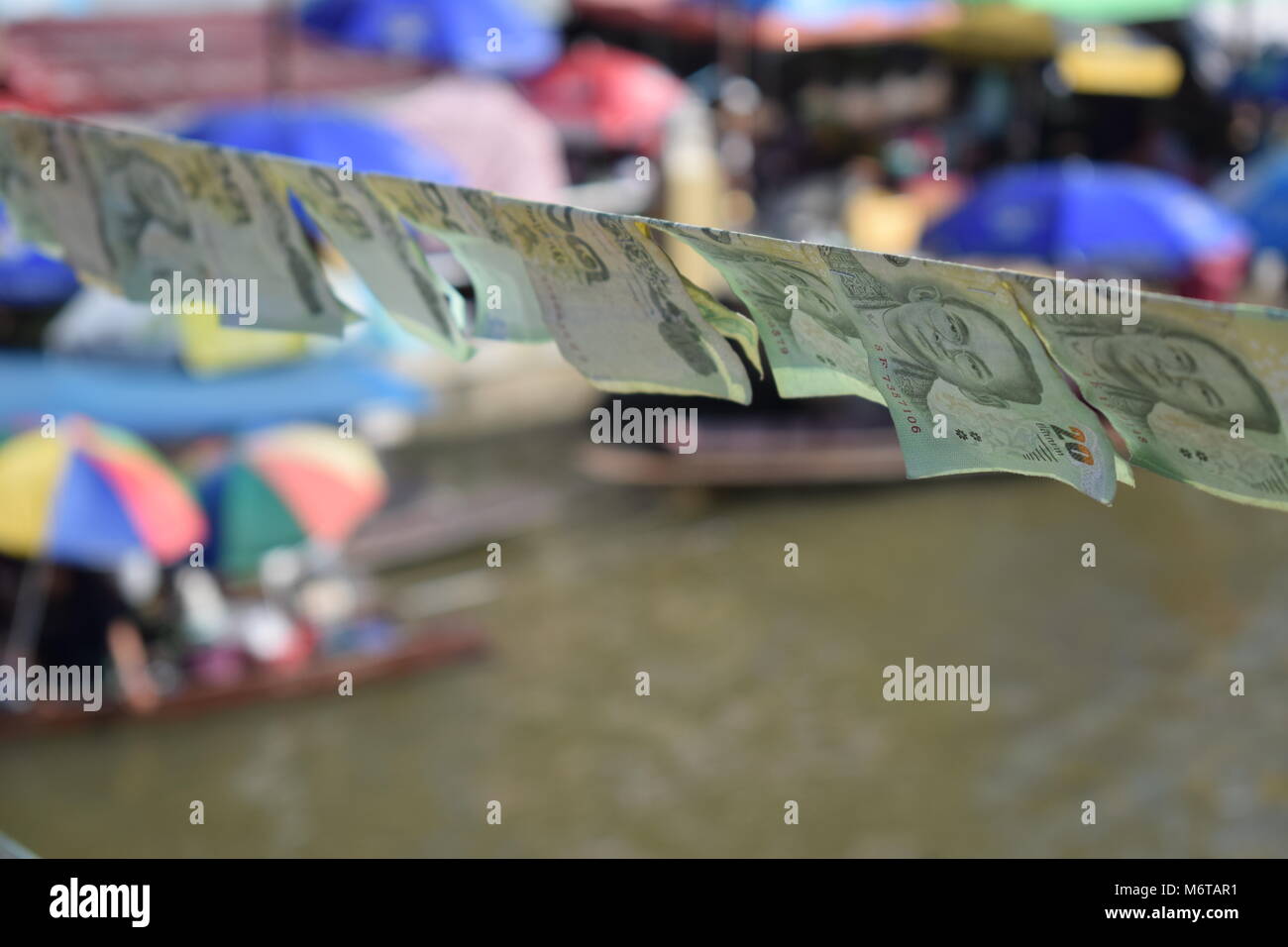 Viele 20 Baht Banknoten in den Fokus auf eine Zeichenfolge in das Angebot der von der Brücke der schwimmenden Markt Amphawa über den MaeKlong Fluss angeschlossen ist verschwommen Stockfoto