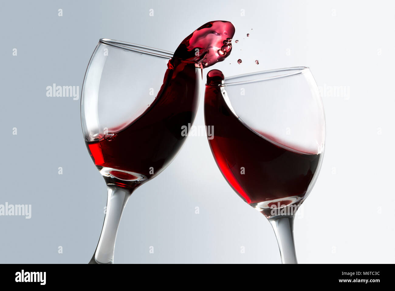 Das Toasten von zwei Gläser Rotwein mit Überlauf Stockfoto