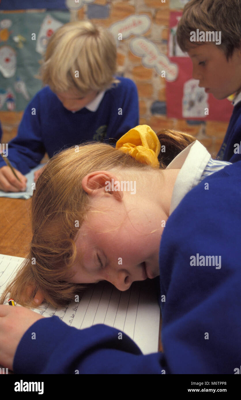 Schüler in der Grundschule Klassenzimmer schlafend am Schreibtisch gefallen Stockfoto