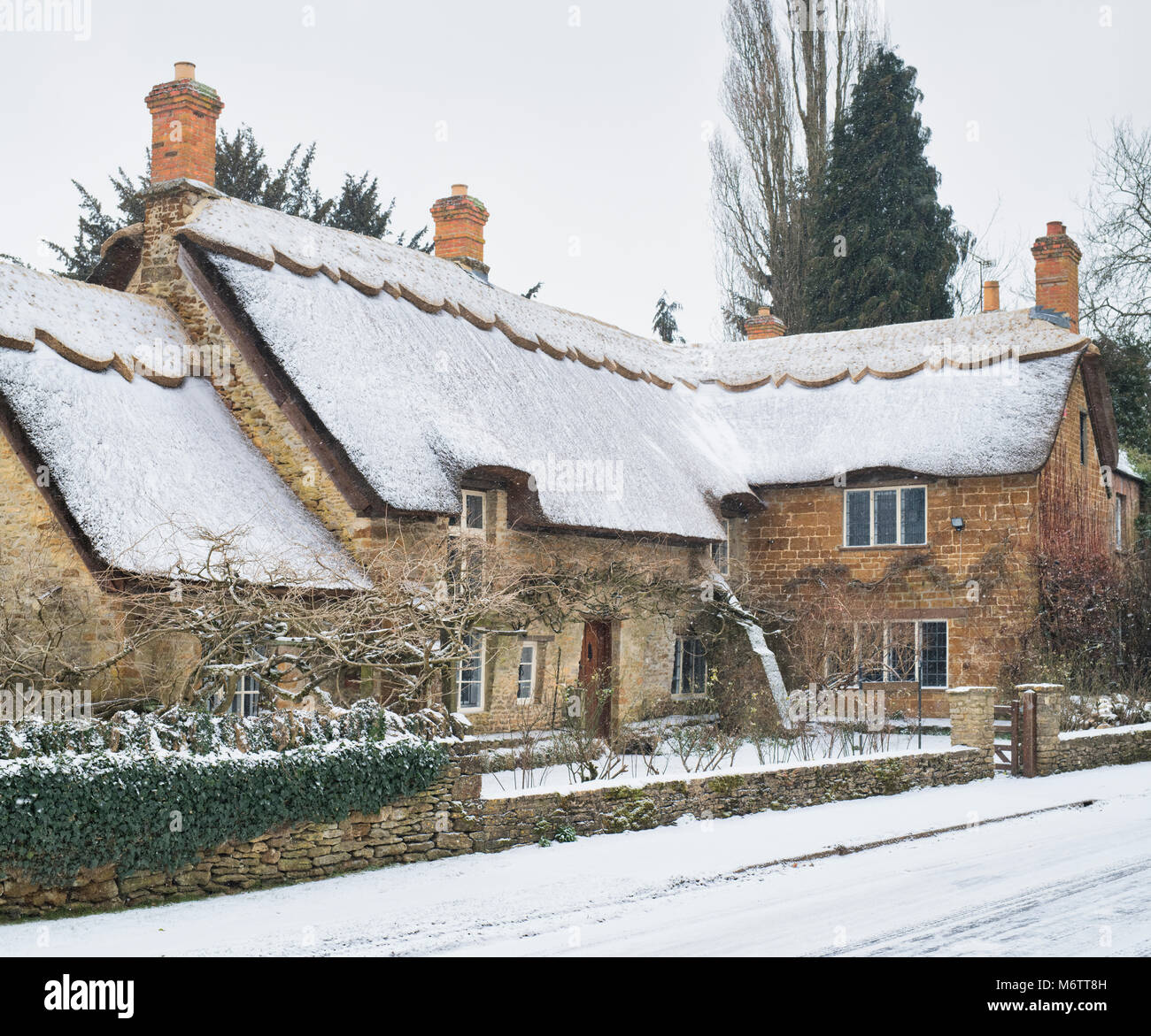 Reetdachhaus in kleinen Tew im Winter Schnee. Wenig Tew, Cotswolds, Oxfordshire, England. Stockfoto