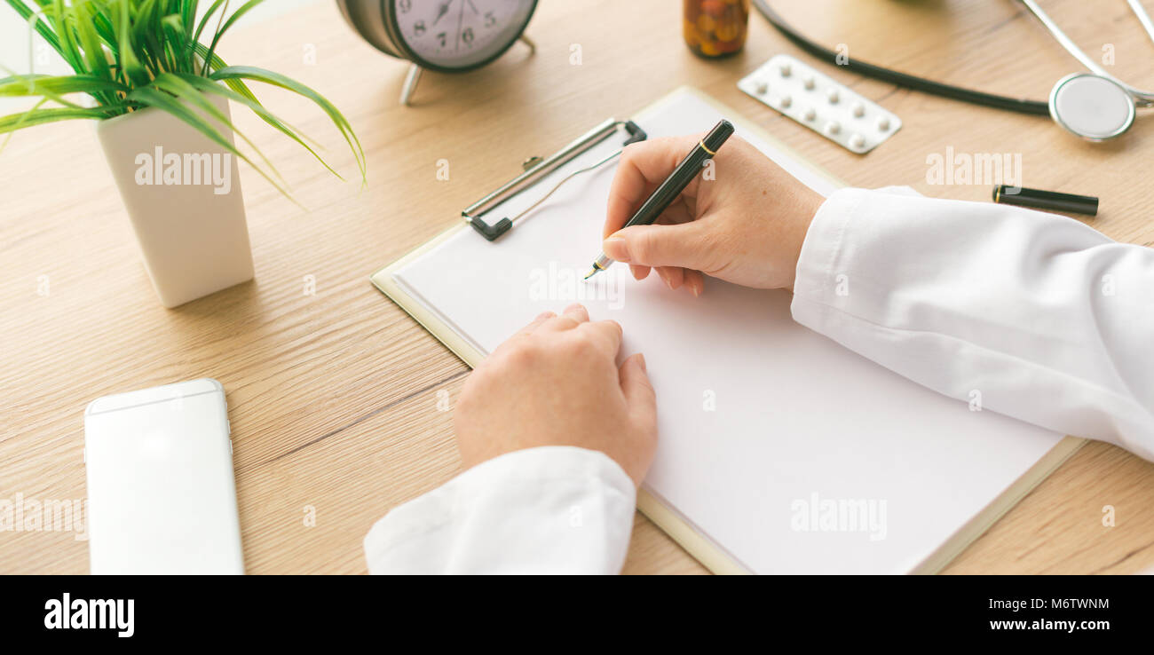 Ärztin Notizen, medizinische Geschichte des Patienten oder Medizin Rezept auf Zwischenablage Papier während der medizinischen Untersuchung im Krankenhaus Büro Stockfoto