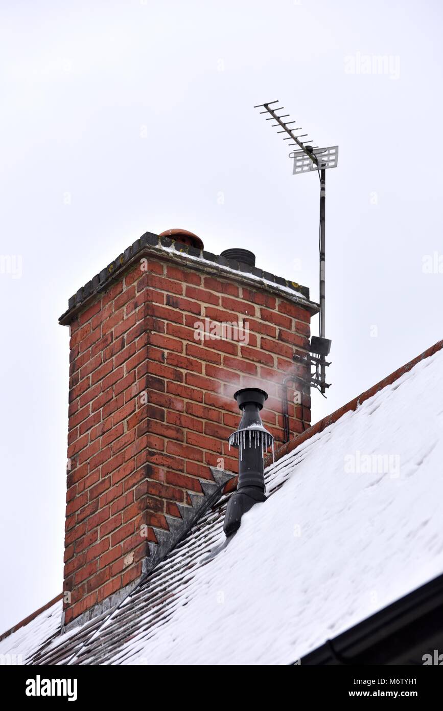 Heimische Zentralheizung Heizkessel Luftdüse auf einem schneebedeckten Dach Stockfoto