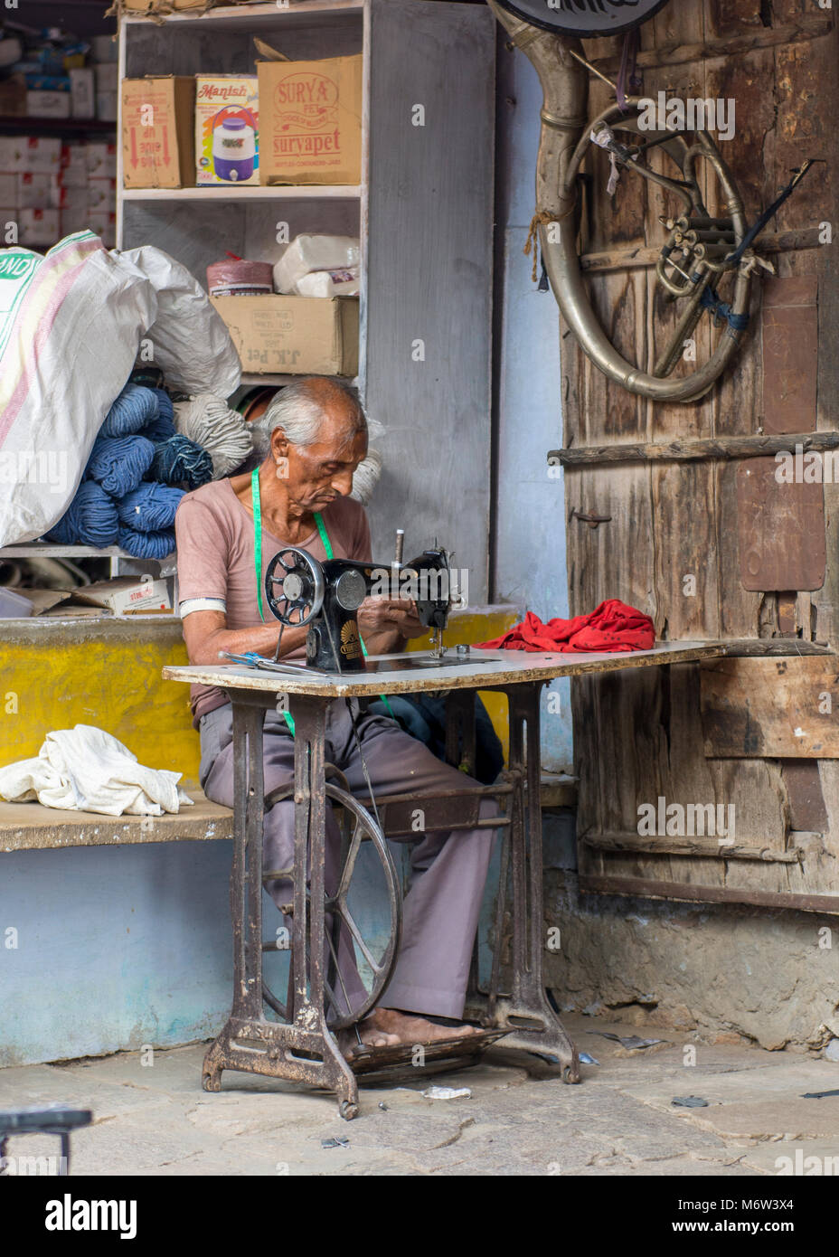 Porträt eines älteren indischen Mann mit einem Tretgerät (Pedal) Nähmaschine außerhalb seines Hauses in Samode Village, Rajasthan, Indien Stockfoto