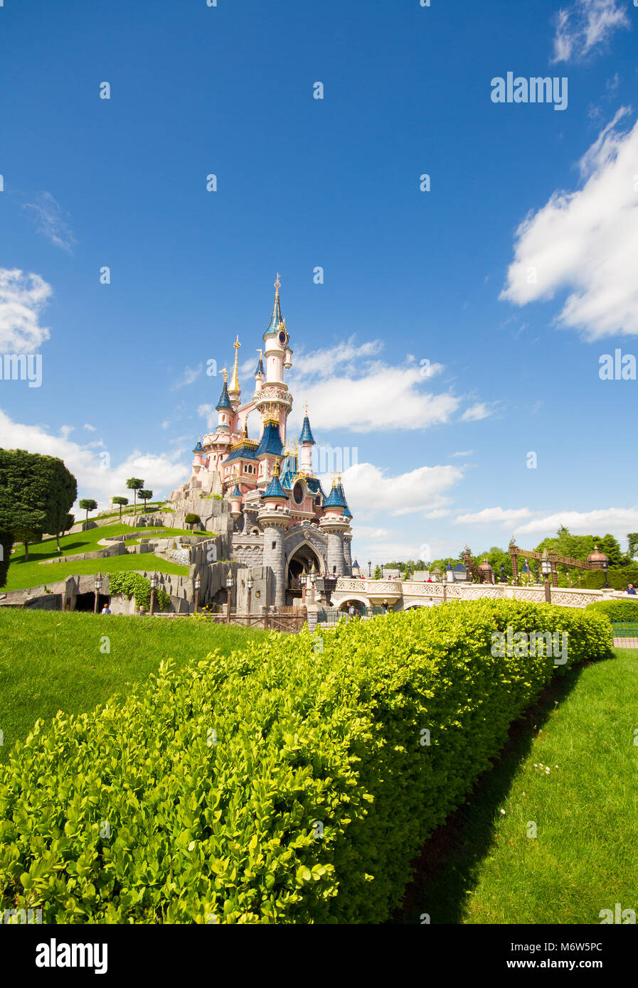 Ein buntes Bild im Hochformat von Dornröschenschloss in Disneyland, Paris mit schönen grünen Gärten und blauen Himmel. Stockfoto