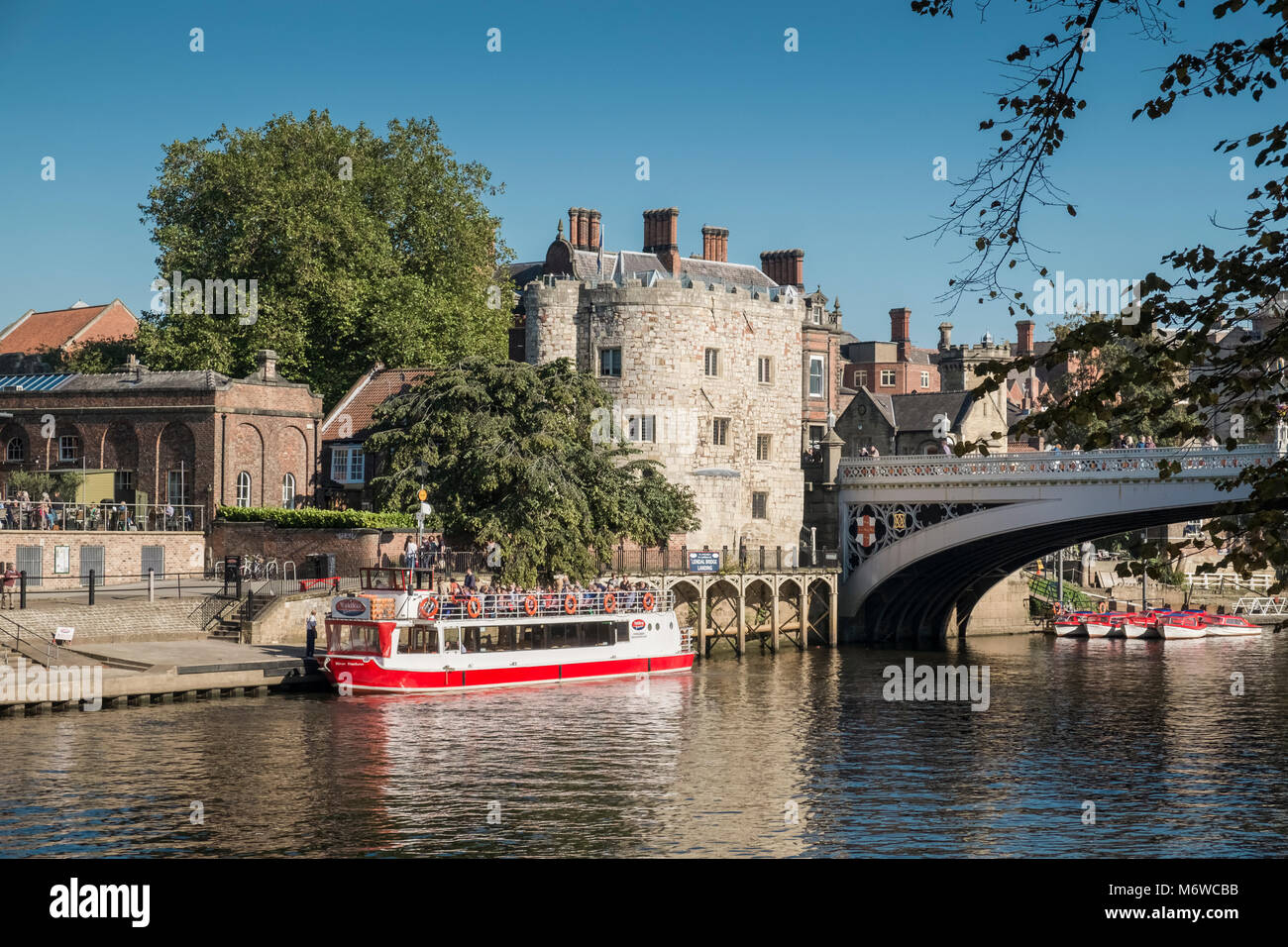 Ein Fluss Kreuzfahrt Schiff liegt in der Nähe von Lendal Tower (ehemals Teil der Yorks mittelalterliche Mauer Abwehr) und Lendal Brücke, Fluss Ouse, York, North Yorkshire, Großbritannien Stockfoto