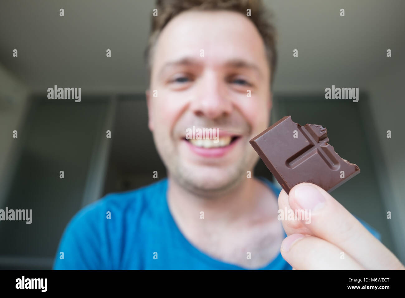 Junge kaukasier Kerl eine Schokolade alleine essen Stockfoto