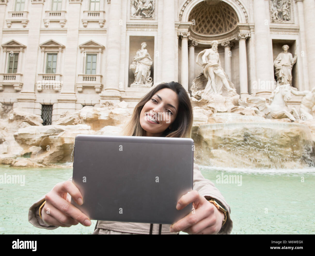 Junge hübsche Frauen kaukasischen Touristische lächelnd tun Selbstportrait mit Tablette mit dem Trevi Springbrunnen im Hintergrund, Rom monument Sehenswürdigkeiten Italien Stockfoto