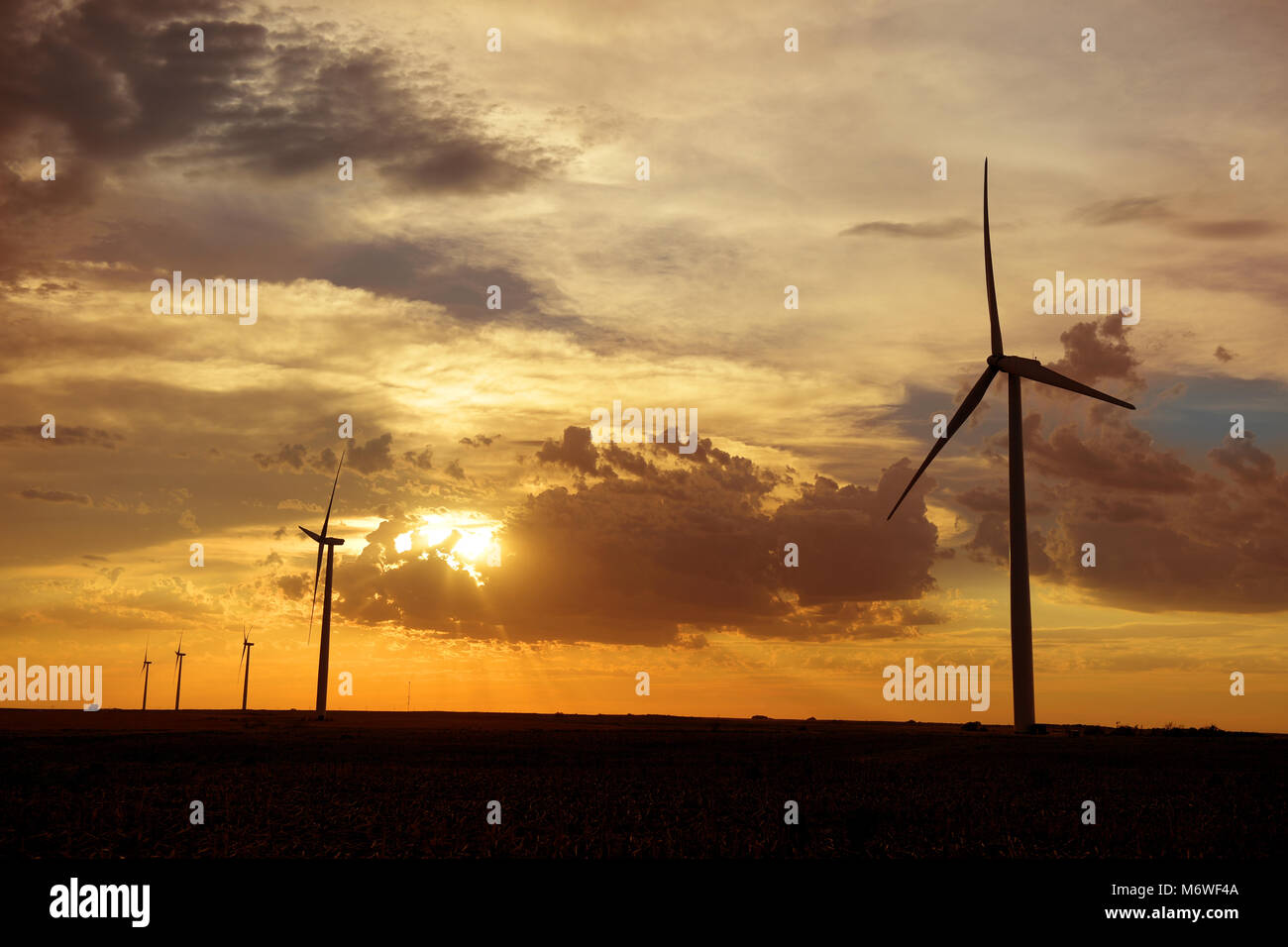 Windenergieanlagen bei Sonnenuntergang auf einer Farm in Kansas Stockfoto
