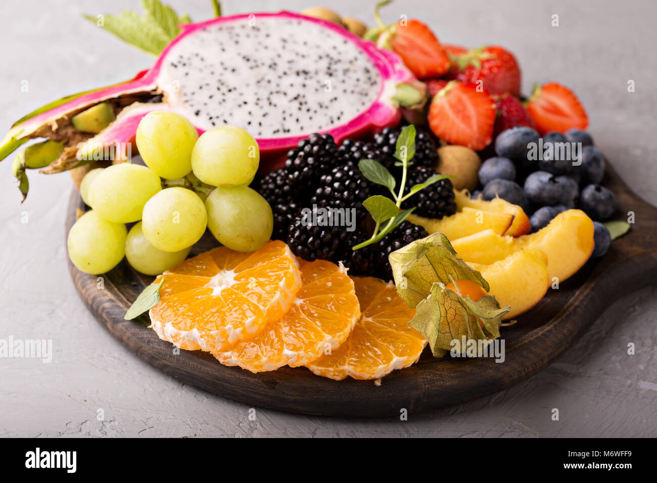 Exotische Früchte Platte mit Trauben, Drachenfrucht, Pfirsich und Beeren Stockfoto
