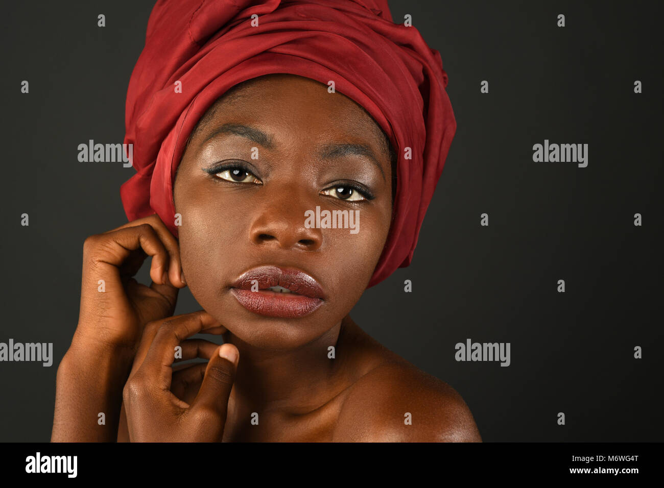 Porträt von Afrikanerin mit roten Turban auf dunklem Hintergrund Stockfoto