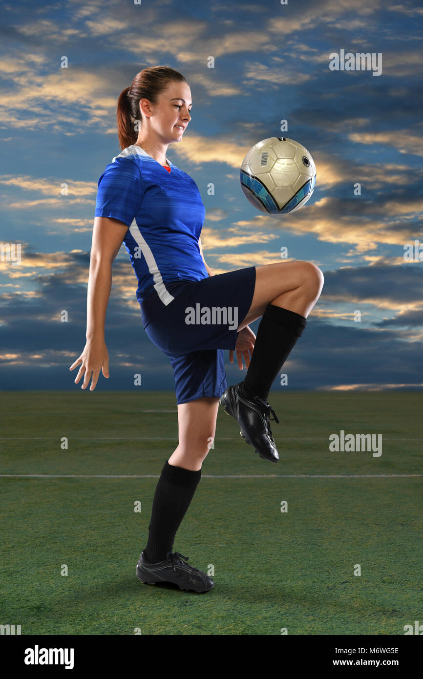 Weiblichen Fußballspieler springenden Ball auf Knie in der Abenddämmerung Stockfoto