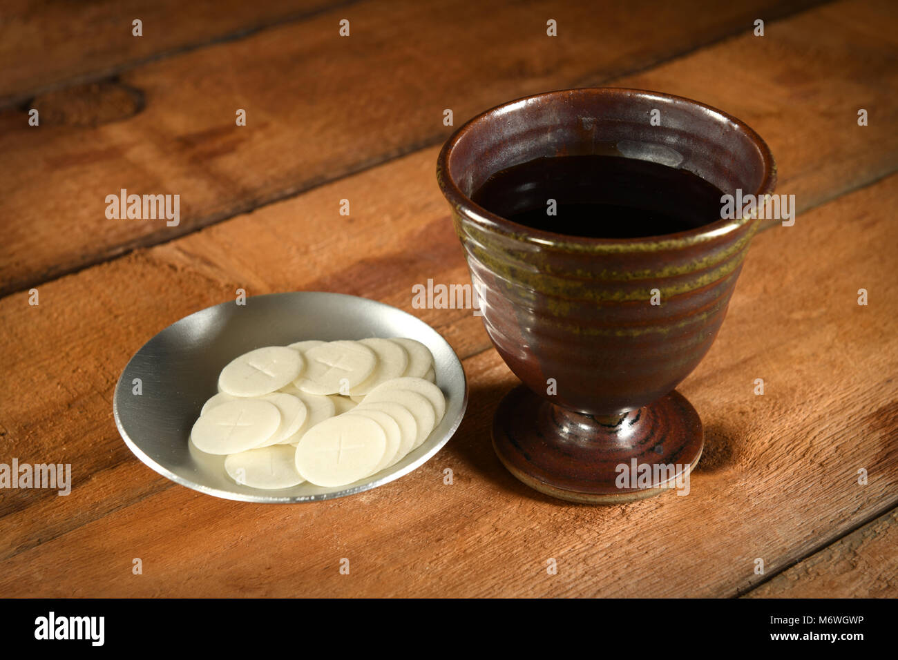 Kommunion-Wafer und Becher Wein auf Holztisch Stockfoto