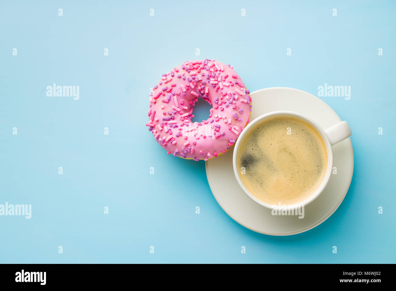 Rosa Donut und Kaffee Tasse auf blauem Hintergrund. Stockfoto