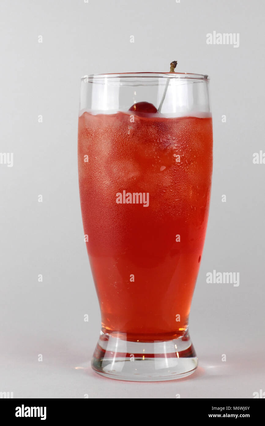 Ein hohes Glas von Red Shirley Temple Drink mit Sahnehäubchen steht vor einem neutralen Hintergrund. Stockfoto