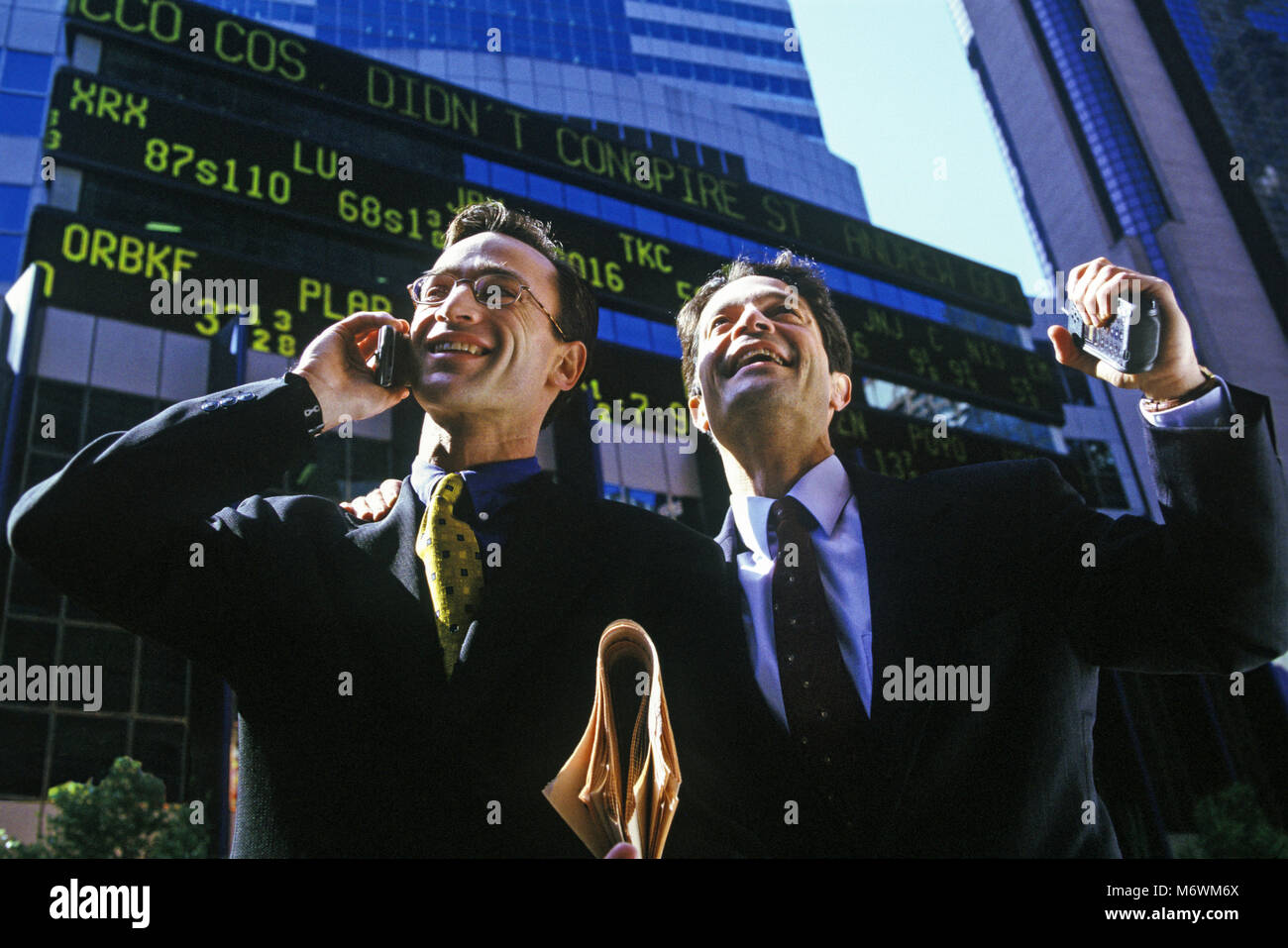 1998 historische KAUKASISCHEN BUSINESS MÄNNER MIT MOBILE MOBILTELEFONE AM BÖRSENKURS TICKER ANZEIGE Stockfoto