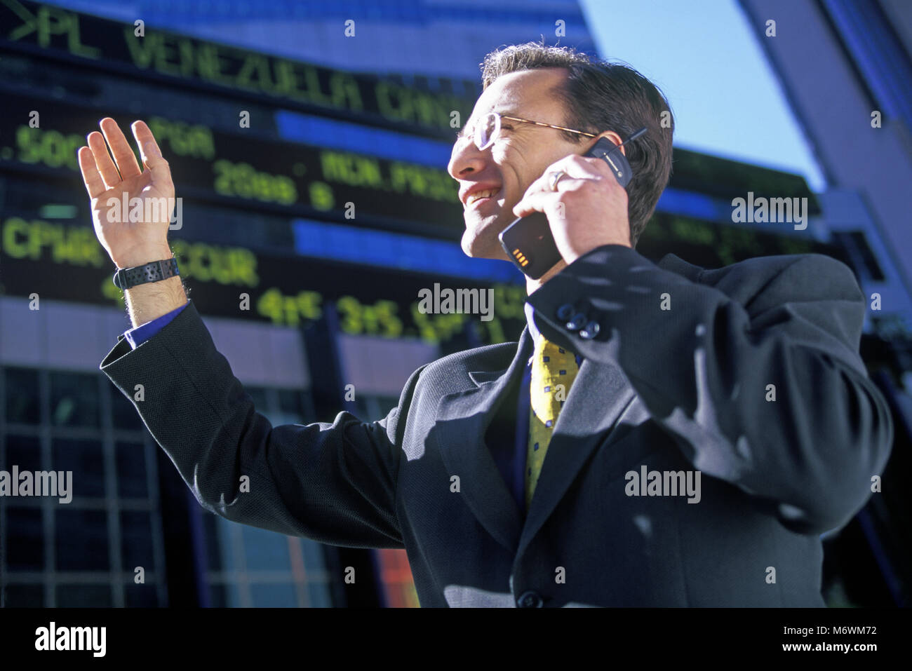 1998 historische KAUKASISCHEN GESCHÄFTSMANN MIT MOBILTELEFON TELEFON AM BÖRSENKURS TICKER ANZEIGE Stockfoto
