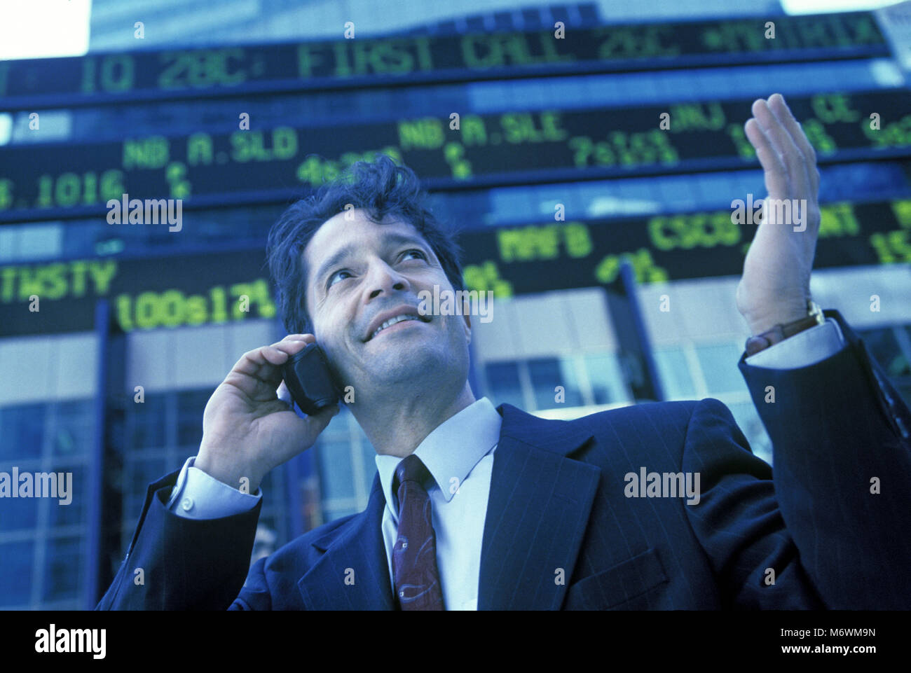 1998 historische KAUKASISCHEN BUSINESS MANN MIT zellulären beweglichen Telefon hinter BÖRSENKURS TICKER ANZEIGE Stockfoto