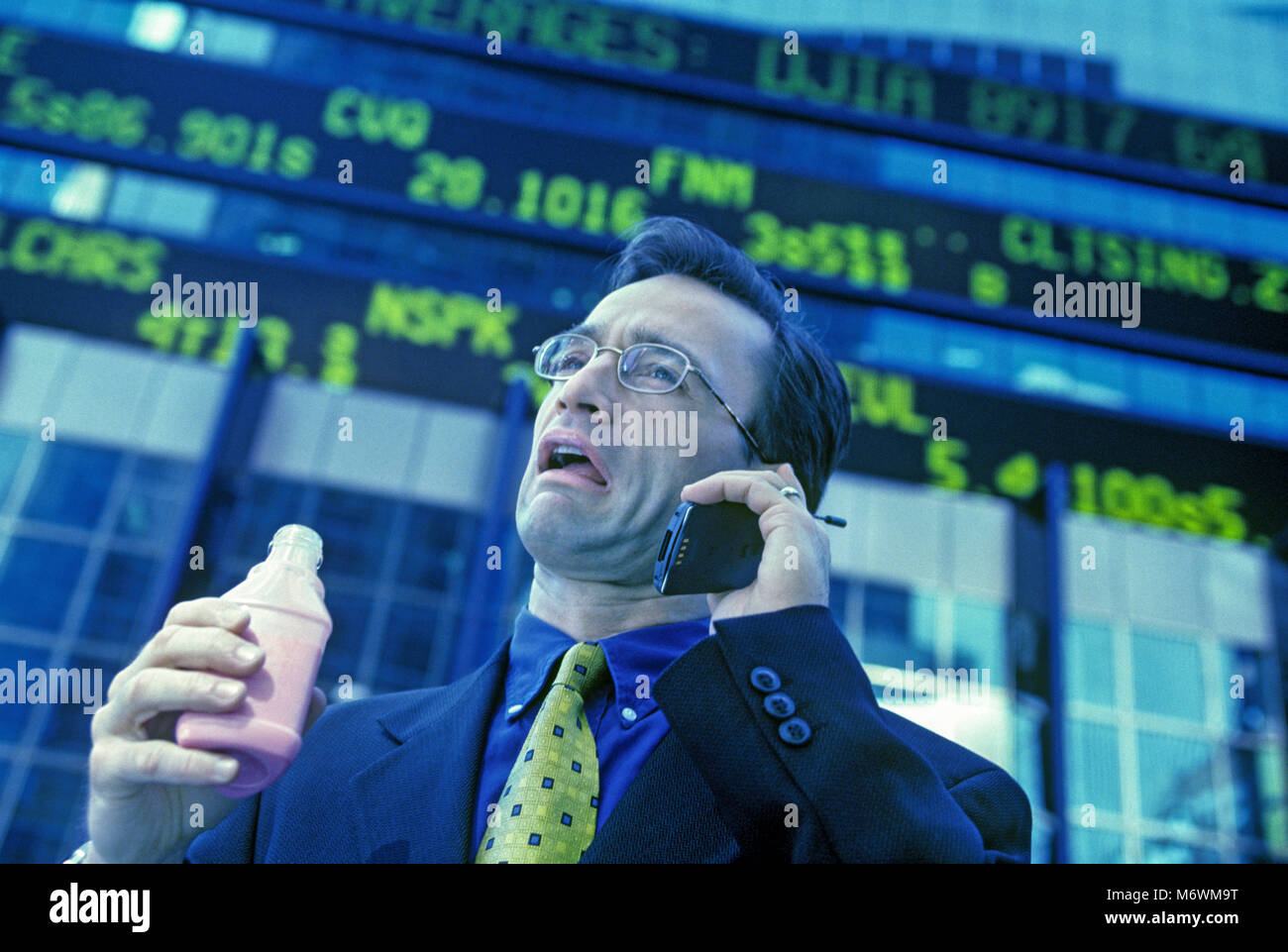 1998 historische KAUKASISCHEN BUSINESS MANN MIT zellulären beweglichen Telefon hinter BÖRSENKURS TICKER ANZEIGE Stockfoto