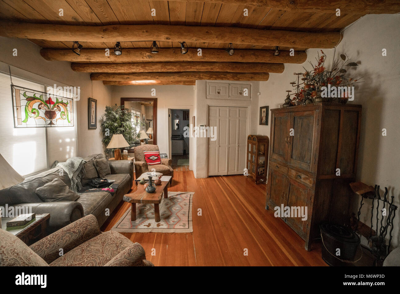 Ein malerisches Santa Fe, New Mexico Wohnzimmer in einem Adobe Architektur Stil mit Holzböden, Decken und weiße Wände. Stockfoto