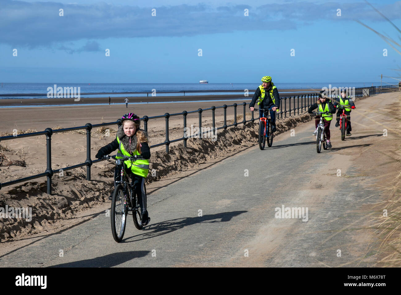 Kinder unter Anleitung Radfahren in Crosby, Merseyside. Wetter in Großbritannien. 7th. März 2018. Sonniger Start in den Ausflugstag auf dem Mariners Way, da Schulkinder auf dem Fahrrad auf dem Mariners Way am Meer trainiert werden. Stockfoto