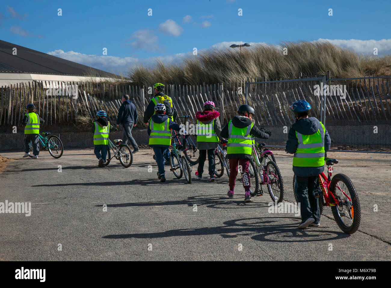 Kinder unter Anleitung Radfahren in Crosby, Merseyside. Wetter in Großbritannien. März 2018. Sonniger Start in den Tag auf dem Mariners Way, während Schulkinder auf dem Fahrrad auf dem Mariners Way an der Strandpromenade trainieren. Stockfoto