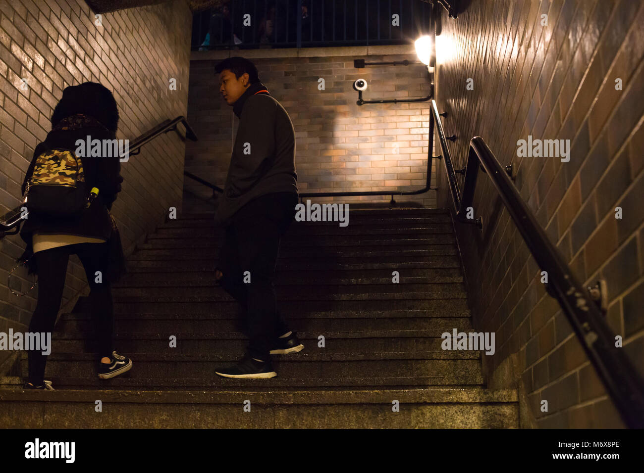 Ein Mann und eine Frau in einem Ziegelstein Treppenhaus bei Nacht mit einigen Spannungen zwischen ihnen. Stockfoto