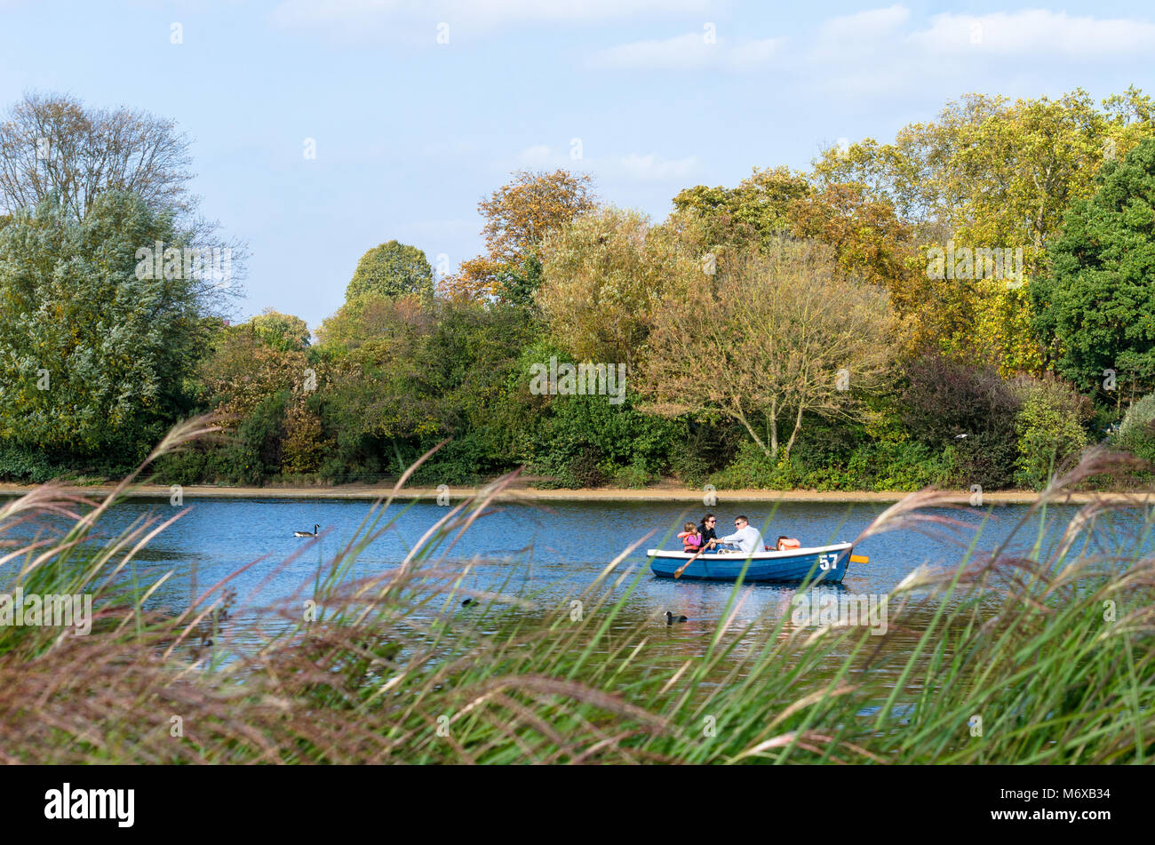 Eine Familie mit einem Ruderboot im Herbst in der Serpentine River im Hyde Park, London Stockfoto