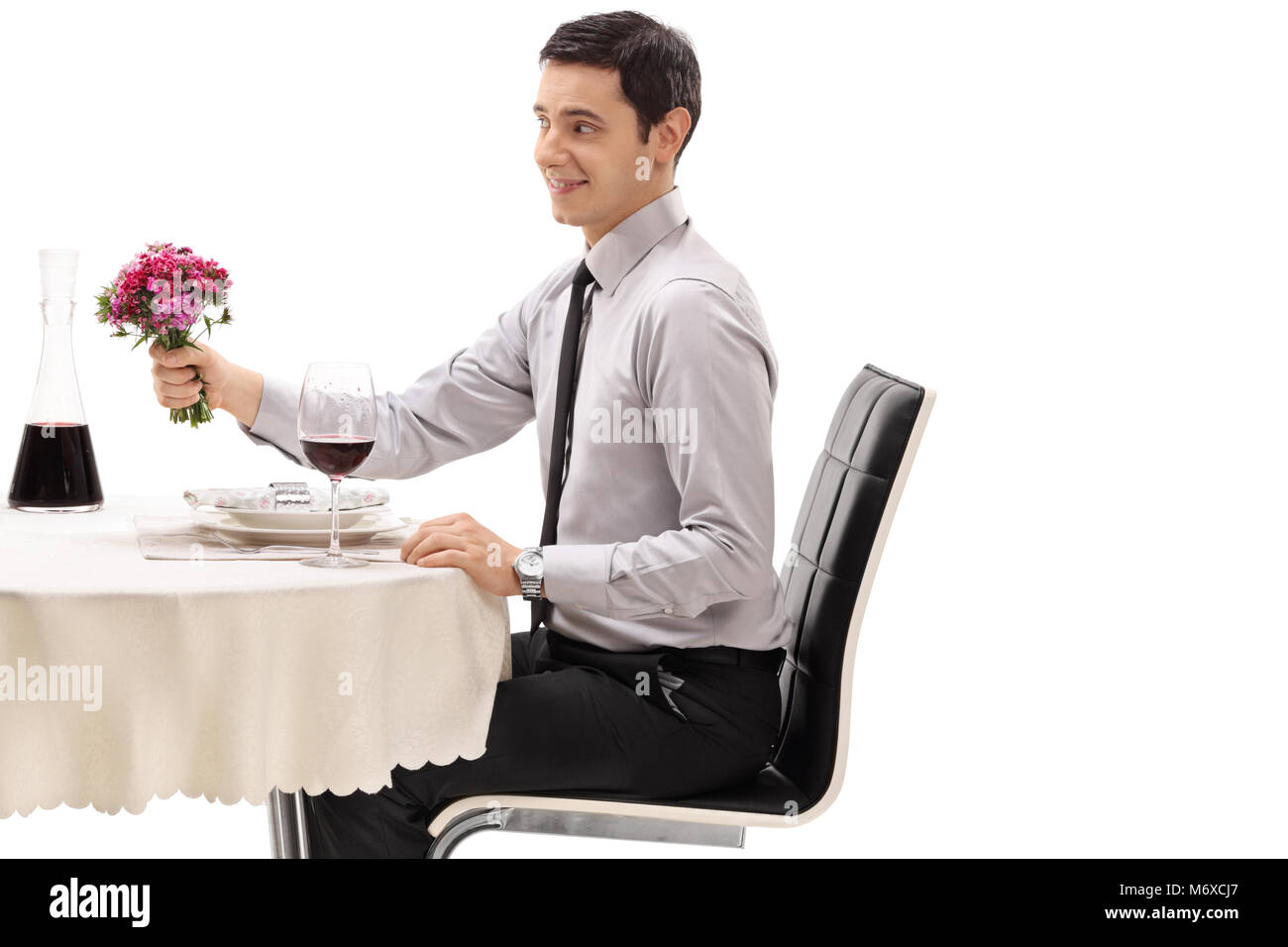 Junge Mann an einem Tisch im Restaurant mit einem Strauß Blumen auf weißem Hintergrund sitzt Stockfoto