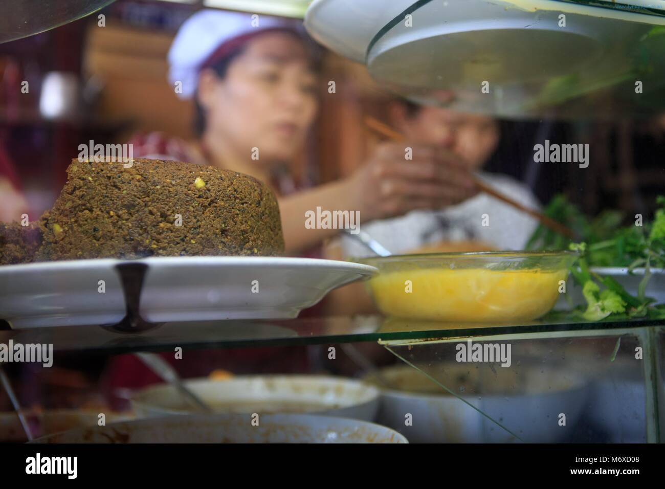 Banh MI Phuong Arbeitnehmer Zubereitung der traditionellen Speisen aus Zutaten, die in einem Glaskasten. Hoi An, Vietnam Stockfoto