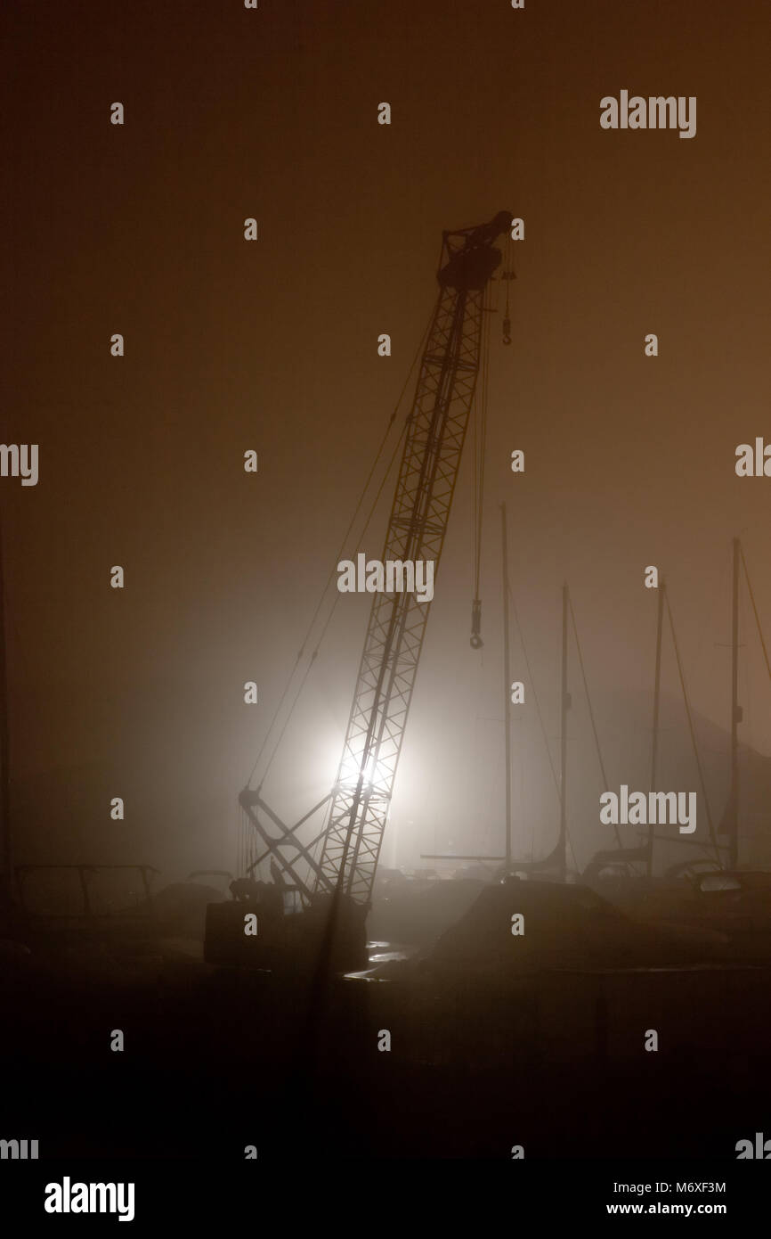 Silhouette von einem Kran auf einem nebligen Nacht Stockfoto