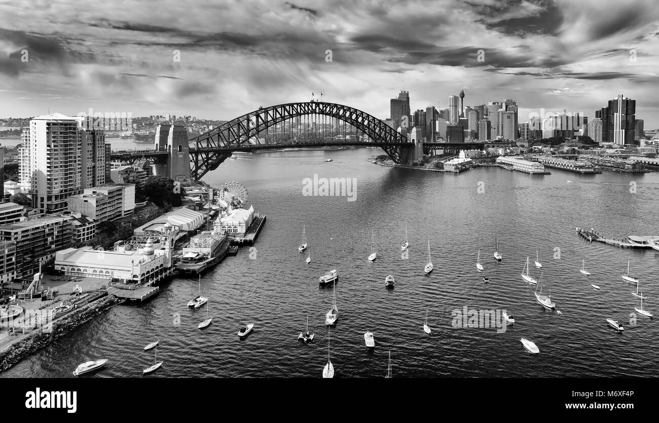 Schwarz Weiß Bild der Stadt Sydney CBD Wahrzeichen über Hafen auf der Sydney Harbour Bridge mit Kontrast atmosphärische Wolken über dem hoch aufragenden Türmen. Stockfoto