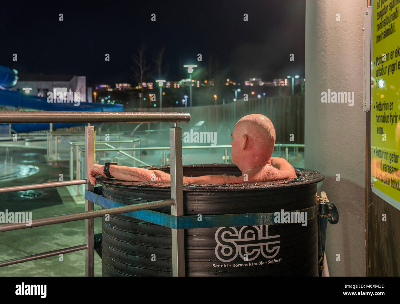 Mann in einem kleinen Whirlpool in einem örtlichen Schwimmbad von Reykjavik, Island Stockfoto