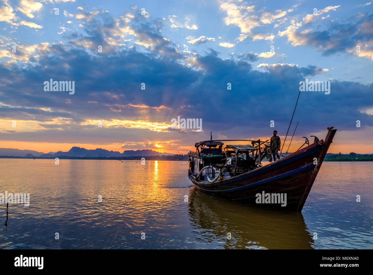 Sonnenuntergang über den Bergen auf der anderen Seite des Saluen Thanlyin Fluss, ein Schiff nähert sich der Küste Stockfoto