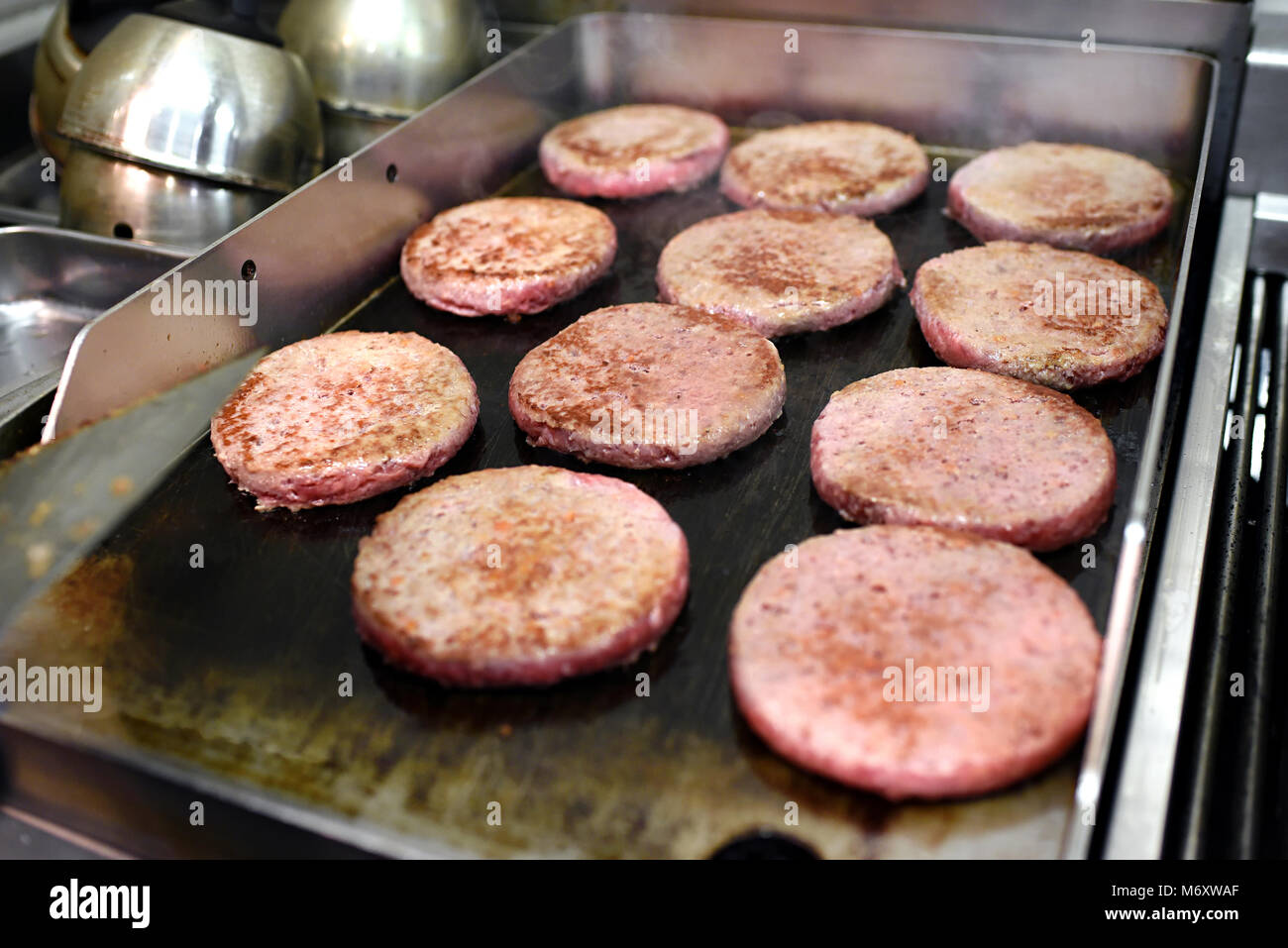 Reihen von ground Beef Burger Frikadellen kochen auf einem heißen Bratpfanne oder Kochplatte in einem Fast-Food-Restaurant in der Nähe zu sehen, der Fleisch- und Gerät Stockfoto
