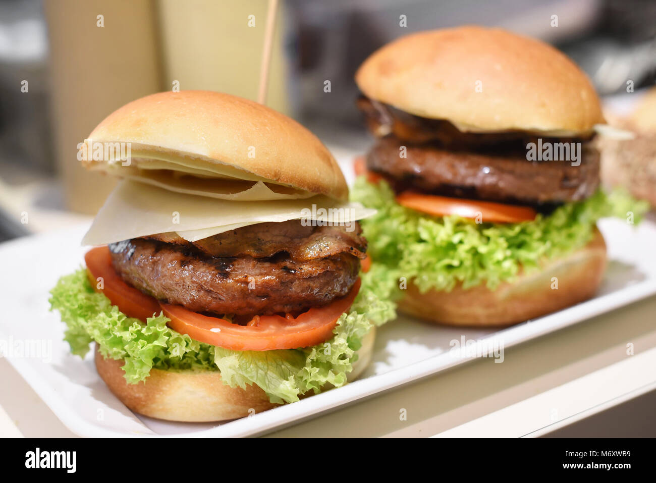 Bereit zum Hamburger auf ein Tablett mit frischem Salat Garnituren, Rindfleisch Patty, Speck gefüllt serviert Essen und geschnittenen Käse auf einem crusty Bun Stockfoto