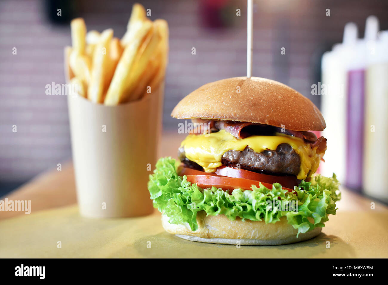 Frische saftige Hamburger oder Cheeseburger mit geschmolzenem Käse über ein Rindfleisch Patty und Salat Zutaten auf ein knuspriges Brötchen mit Pommes frites serviert. Stockfoto