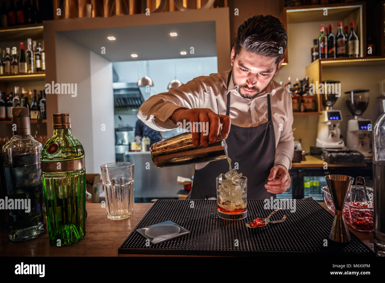 Männliche Barkeeper macht Cocktail Shaker gießen Alkohol aus Glas an der Bar Hintergrund Stockfoto