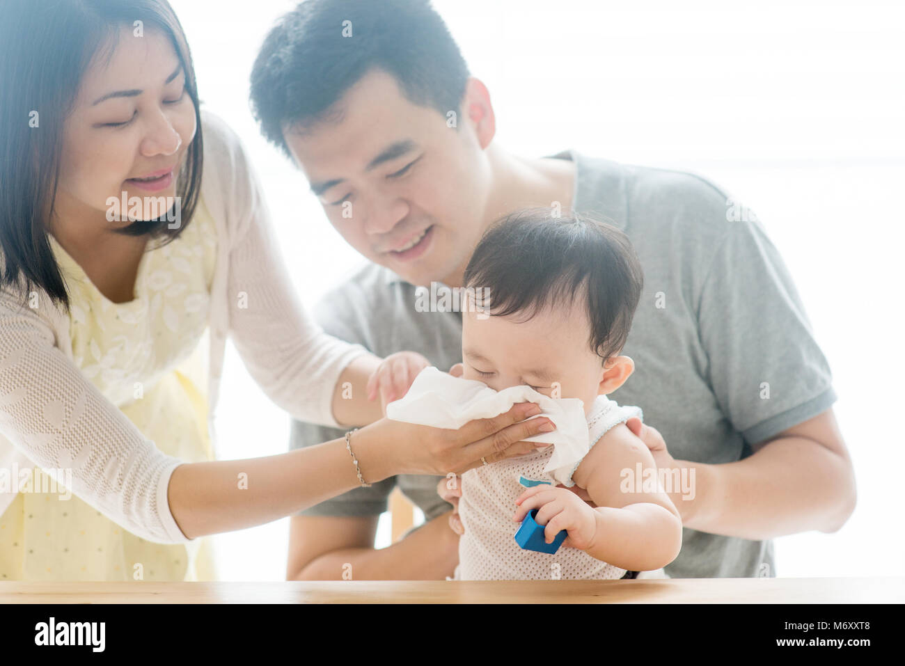 Mutter Feuchttücher baby Nase mit Seidenpapier. Asiatische Familie viel Zeit zu Hause, lebende Lebensstil im Innenbereich. Stockfoto