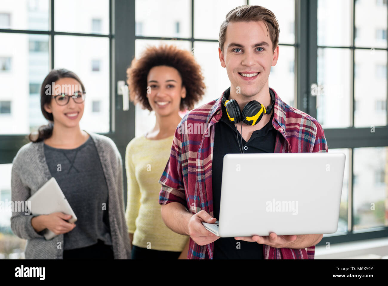 Portrait der junge Mann lächelnd, während Sie einen Laptop bei der Arbeit Stockfoto