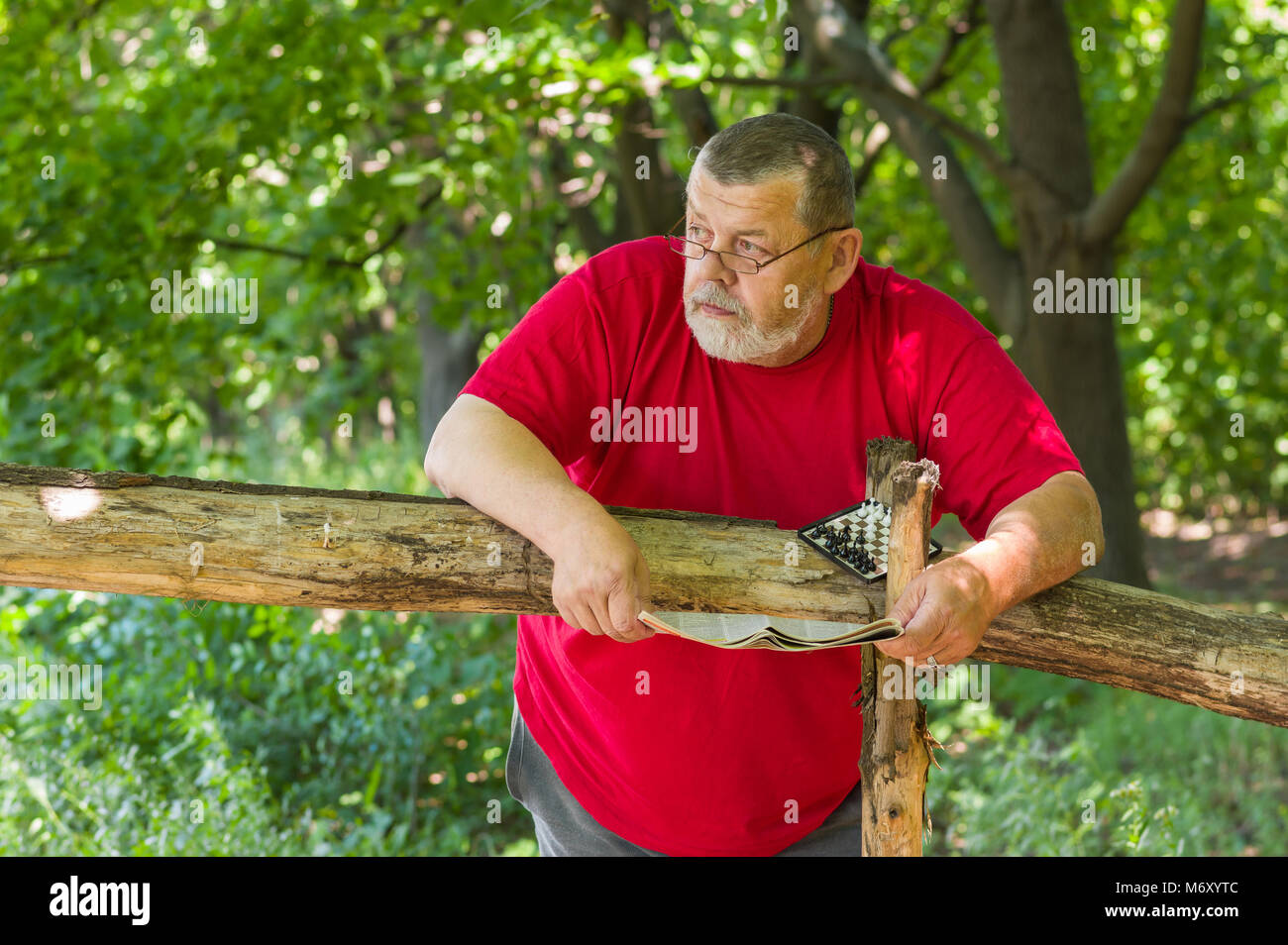Portrait von älteren bärtigen Mann mit Zeitung und Mini - Schach im Sommer Park Stockfoto