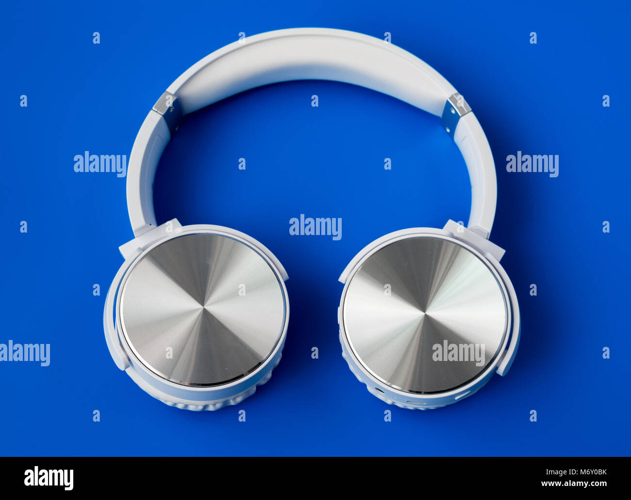 White wireless Bluetooth Kopfhörer auf blauem Hintergrund Stockfoto