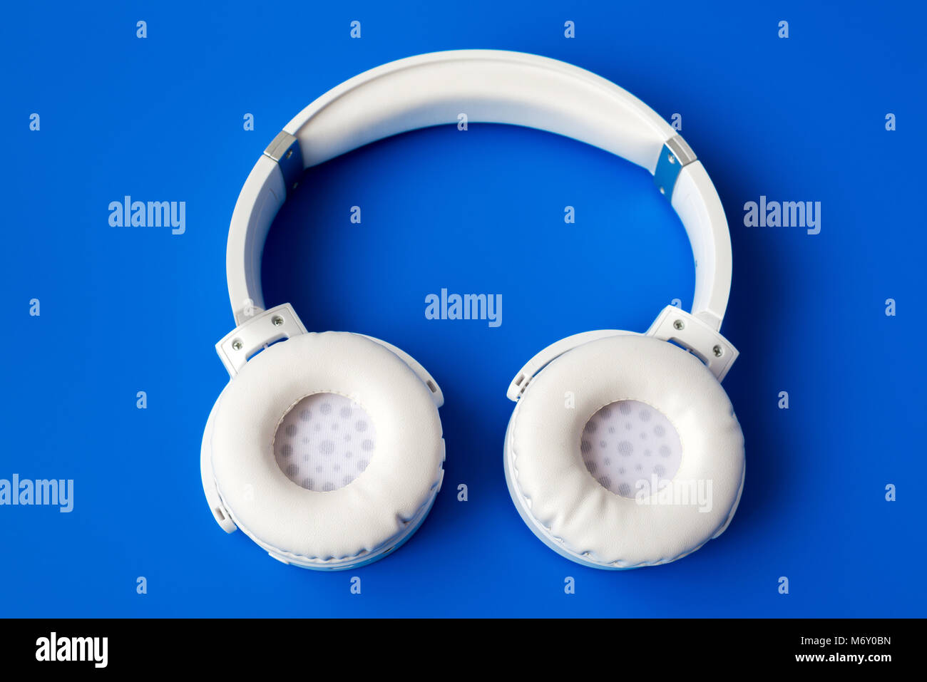 White wireless Bluetooth Kopfhörer auf blauem Hintergrund Stockfoto