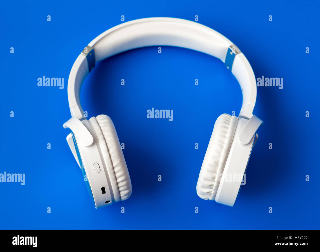 White wireless Bluetooth Kopfhörer auf blauem Hintergrund Stockfoto