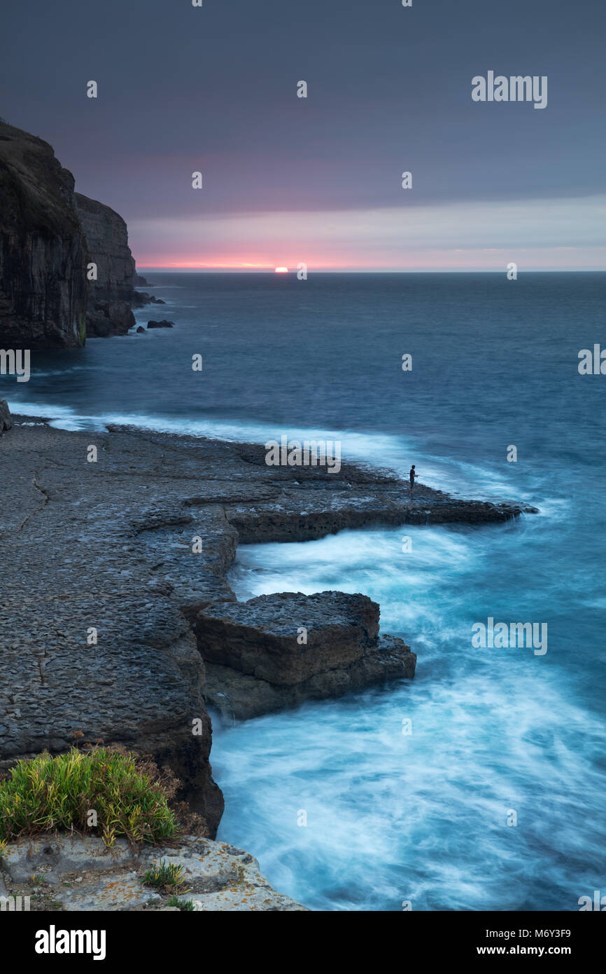 Einen einsamen Angler auf Dancing Ledge in der Morgendämmerung, Jurassic Coast, Dorset, England, Großbritannien Stockfoto
