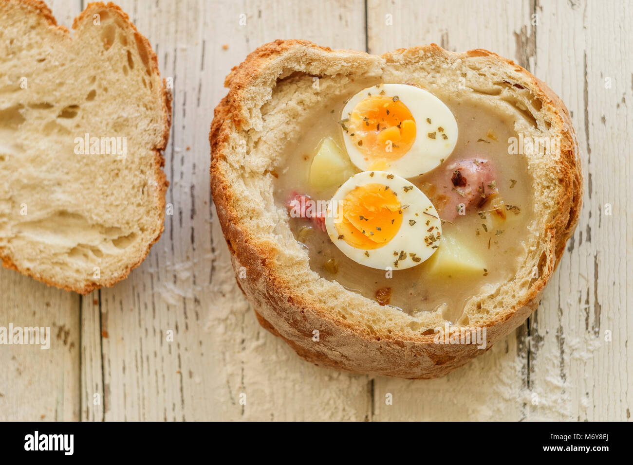 Traditionelle polnische Suppe namens Zurek mit Eiern und Würstchen auf hölzernen Hintergrund Stockfoto