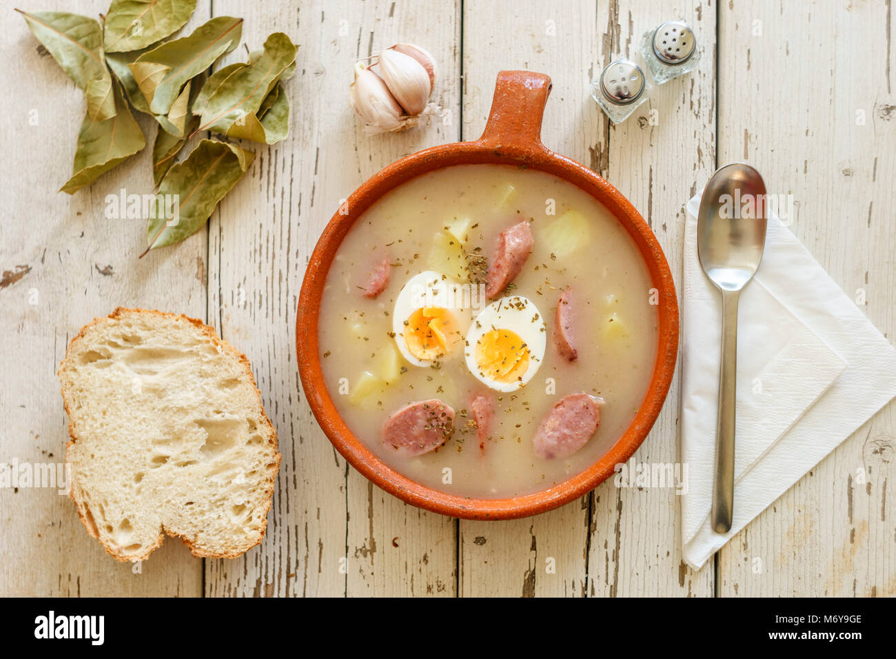 Traditionelle polnische Suppe namens Zurek mit Eiern und Würstchen von Gewürzen umgeben Stockfoto