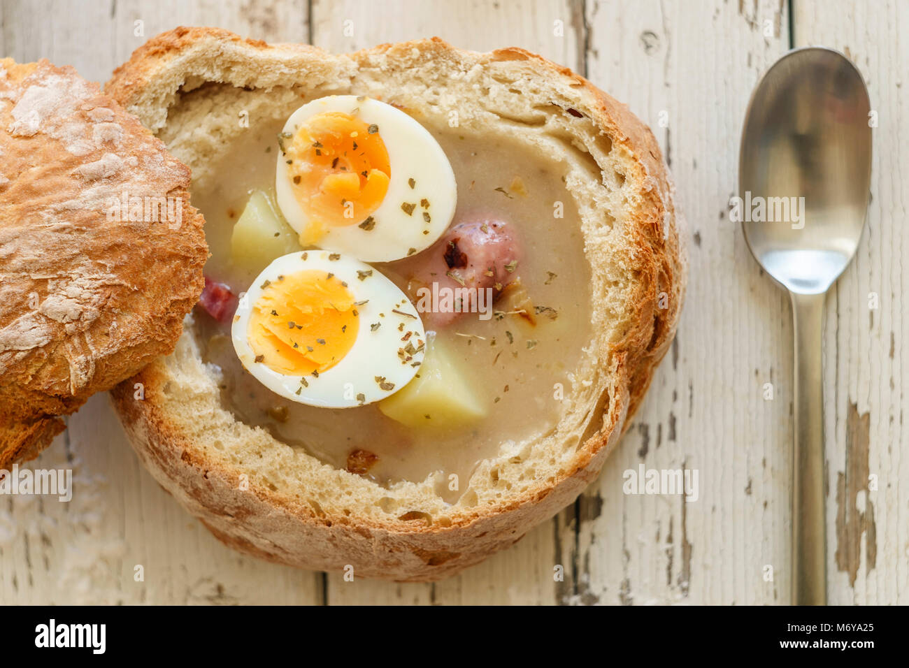 Traditionelle polnische Suppe namens Zurek mit Eiern und Würstchen auf hölzernen Hintergrund Stockfoto