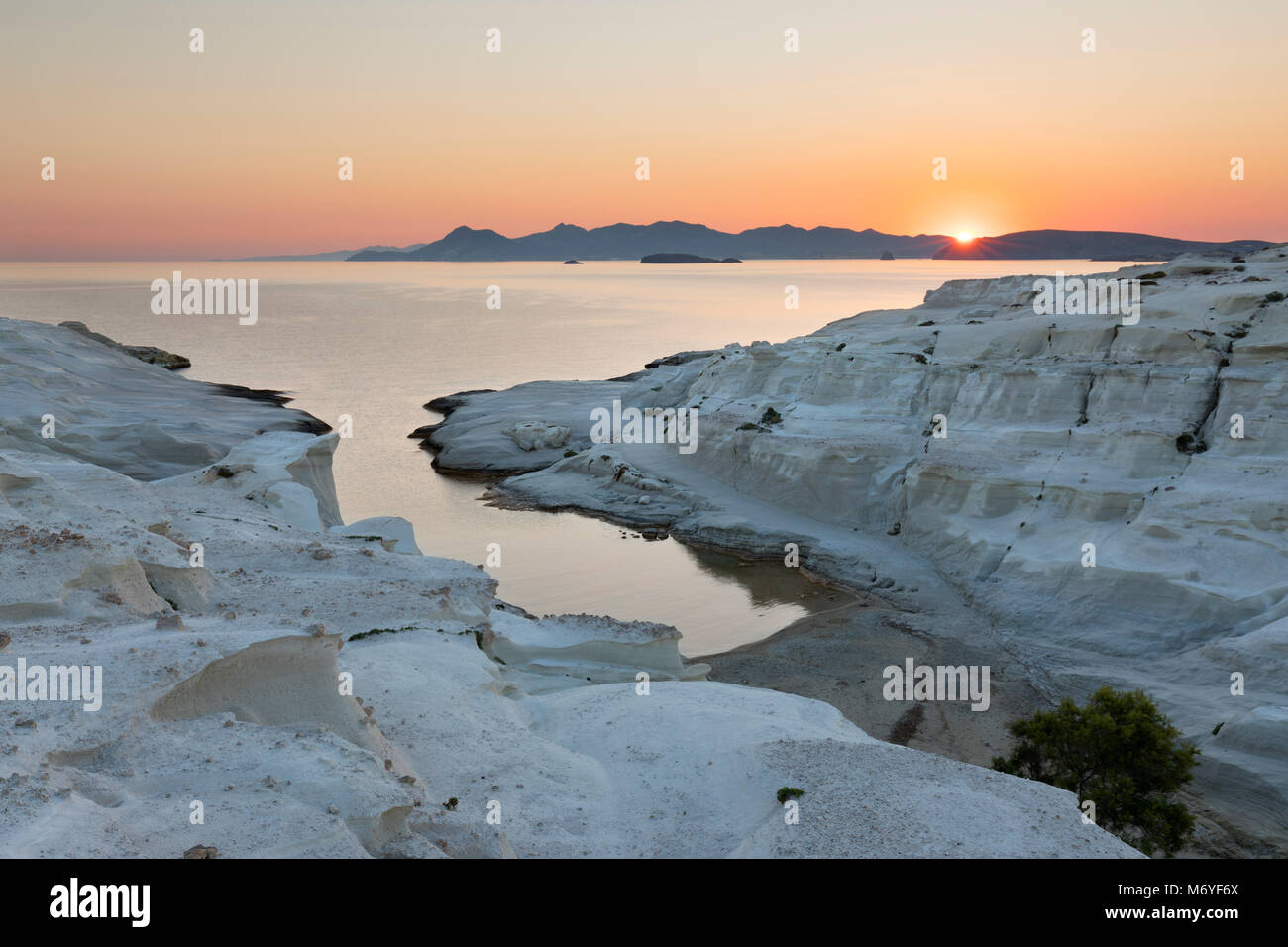 Strand und vulkanische Felsformationen bei sarakiniko an der Nordküste mit Sonnenaufgang über Kimolos Insel in Distanz, Sarakiniko, Milos, Kykladen, Ägäis S Stockfoto
