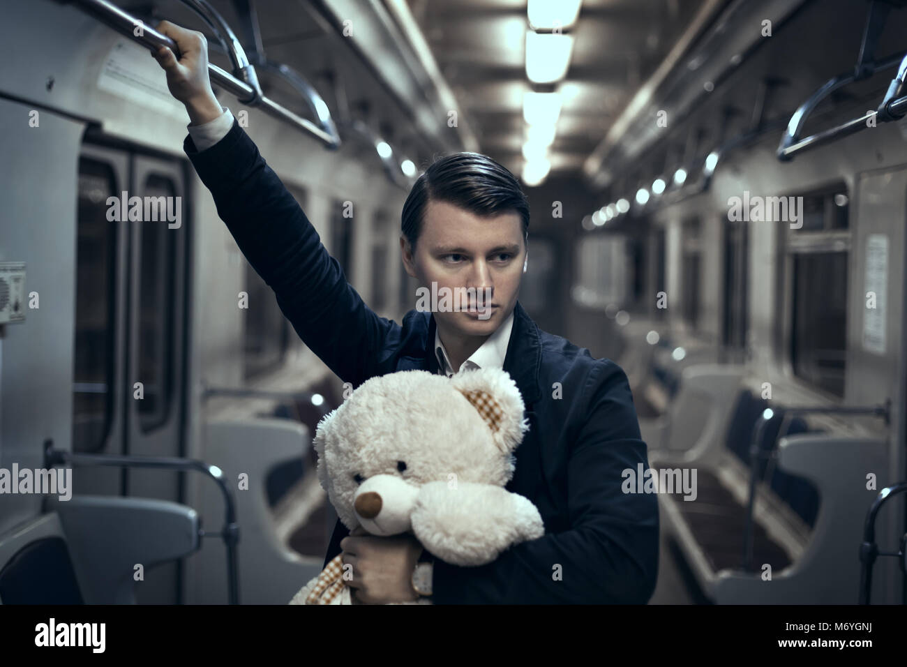 Kerl mit einem Teddybär in der U-Bahn. In ein leeres Auto er einsam ist, macht es ihn traurig. Stockfoto